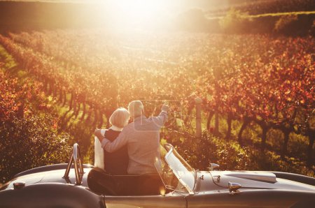Romantisches Seniorenpaar und Oldtimer auf dem Lande zur Weinprobe, zum gemeinsamen Drink oder zu Erinnerungen auf dem Weinberg. Rentner und reife Frau zu Besuch auf dem Bauernhof für Feier, Date oder Roadtrip.
