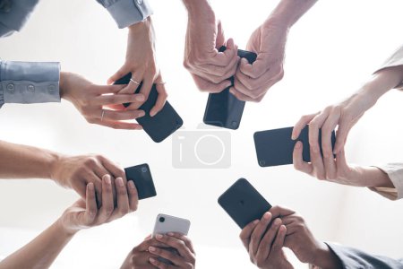 Photo for Hands, business people and phones in circle, low angle and teamwork for networking in office. Colleagues, website and internet for social media research, solidarity and online unity for web survey. - Royalty Free Image