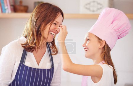 Téléchargez les photos : Mère, fille et nez jouent pendant la cuisson dans la cuisine, le soutien et l'apprentissage de l'enfant à préparer des biscuits. Bonne fille, maman et l'éducation de la pâtisserie à la maison, l'amour et la liaison tout en cuisinant des collations ou des desserts. - en image libre de droit