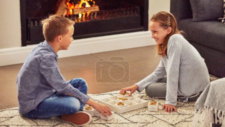 Photo for Children, board game in home on floor with smile, bonding and strategy on holiday for challenge. Siblings, boy and girl in lounge, tic tac toe or excited in contest, versus or happy in family house. - Royalty Free Image