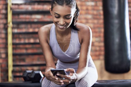 Photo for Happy woman, fitness and browsing with phone at gym for online search on workout or exercise. Young female person with smile on mobile smartphone for training tips, news or app at indoor health club. - Royalty Free Image