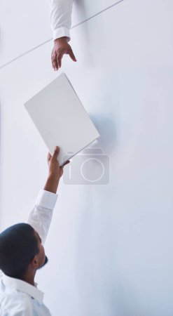 Photo for Documents, exchange and hands with business man passing file to colleague in office for assistance. Help, reach and paper with employee giving folder to coworker on white wall background in workplace. - Royalty Free Image