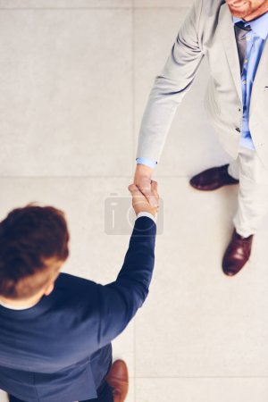 Téléchargez les photos : Homme d'affaires, poignée de main et réunion avec le partenariat ci-dessus pour accord, b2b ou traiter ensemble au bureau. Vue d'ensemble de l'employé ou des collègues serrant la main pour le travail d'équipe, l'unité ou merci au travail. - en image libre de droit