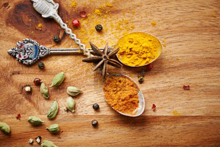Photo for Spoons, spice and selection of seasoning for cooking on kitchen table, turmeric and cardamom for meal. Top view, condiments and options for spicy gourmet in Indian culture, art and food preparation. - Royalty Free Image