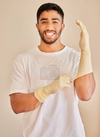 Photo for Cleaning, gloves and portrait of man with smile for work, service and maintenance on white background. Indian person, pride and happy with hygiene accessory for hospitality job, health and safety. - Royalty Free Image