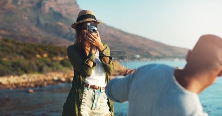 Photo for Couple, photography and beach with camera for trip, memory or outdoor moment together in nature. Woman or photographer taking picture of man, boyfriend or partner on adventure by ocean coast. - Royalty Free Image