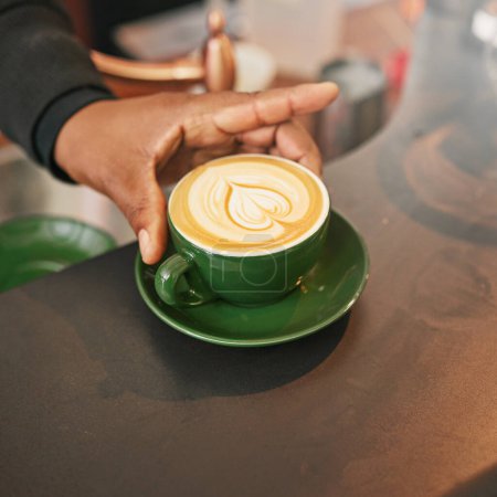 Foto de Mano, taza de café y arte latte para la creatividad, primer plano de cappuccino o bebida de cafeína en el mostrador con barista. Persona con bebida caliente, espuma y leche con diseño, hospitalidad y servicio en la cafetería. - Imagen libre de derechos