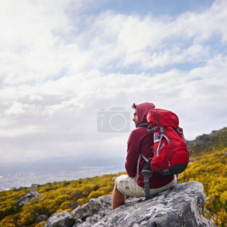 Photo for Man, rock and relax on outdoor hike in nature, mountain and peace or calm in wilderness. Person, exercise and travel with backpack on vacation by cloudy sky, adventure and explore bush for fitness. - Royalty Free Image