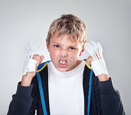 Photo for Portrait, angry and boy with fist, child and expression with frustrated on grey studio background. Face, bully and kid with forks for claws and reaction with costume and aggressive with rage or fight. - Royalty Free Image
