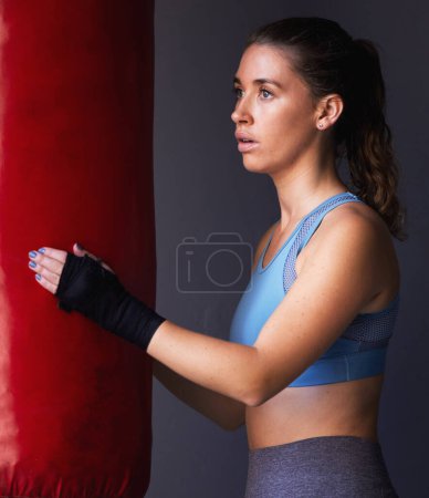 Photo for Sport, boxing bag and woman for fitness in studio as fighter training, exercise and workout in gym for competition. Active, female person and physical activity for health, wellness and self defence. - Royalty Free Image