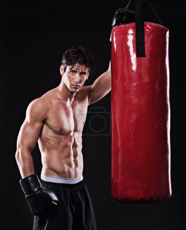 Photo for Boxing, man and portrait in studio with punching bag for workout, exercise or fight competition with dark background. Gloves, boxer and serious male athlete for confidence, martial arts and fitness. - Royalty Free Image
