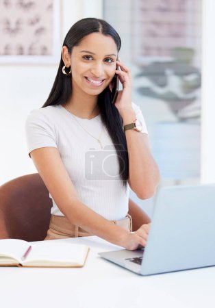 Photo for Indian woman, portrait and phone call at laptop in office as web designer at creative agency, networking or startup. Female person, notebook and cellphone at desk for market research, graphic or chat. - Royalty Free Image