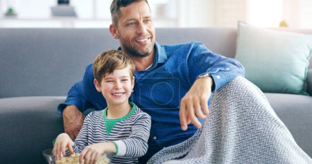 Photo for Relax, dad and son watching tv on sofa in home with popcorn, online video or streaming movie together. Film, father and child on couch for television, cartoon subscription, smile and weekend bonding. - Royalty Free Image