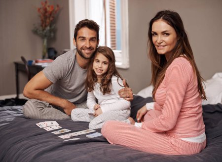 Photo for Parents, girl and playing cards with portrait for fun with bonding, learning or game with strategy in home on bed. Father, mother and daughter in bedroom, love or teaching with pride in family house. - Royalty Free Image