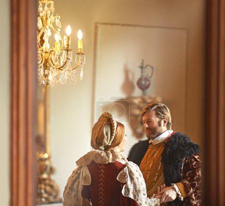 Victorian, man and woman talking in royal castle together with vintage love, romance and banquet hall. Medieval king, queen or renaissance couple in ballroom holding hands with conversation in palace.