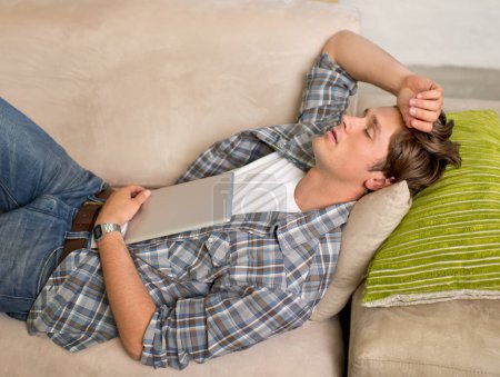 Foto de Casa, hombre y dormir en el sofá con la tableta para relajarse, cansado y ver para el entretenimiento con series de streaming. Bienestar, sala de estar y sofá para descansar con en línea, navegar y cómodo - Imagen libre de derechos