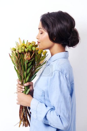Photo for Women, bouquet and flowers in studio for smell and botany for leaves with stem for bloom. Mexican lady and young person holding plant for spring, blossom and bunch for gift and green with eyes closed. - Royalty Free Image