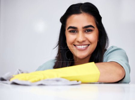 Photo for Indian woman, portrait or cleaner with spray bottle for table, kitchen counter or dirty furniture in home. Smile, maid or janitor washing messy surface with product, liquid soap or cloth with gloves. - Royalty Free Image