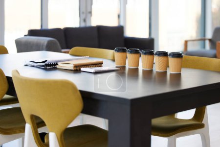 Empty office, meeting room and coffee on table with paperwork, seminar setup or advisory business workshop. Notebook, paper cup and furniture in boardroom at consulting agency for training conference.