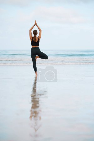 Téléchargez les photos : Équilibre, fitness et yoga avec femme sur la plage pour la paix intérieure, la santé mentale ou le bien-être le matin. Exercice, méditation et zen avec dos de la personne sur le sable par l'océan pour l'entraînement holistique ou l'entraînement. - en image libre de droit
