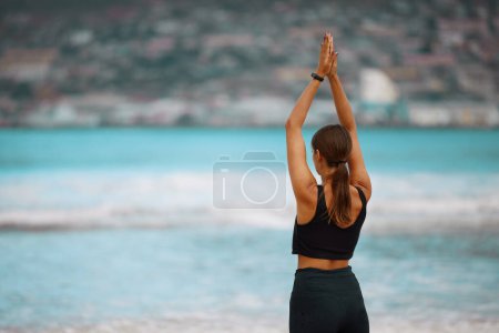 Foto de Ejercicio, meditación y yoga con la mujer en la playa para la conciencia, el equilibrio o el bienestar en la mañana. Fitness, mindfulness y zen con espalda de persona sobre arena por mar para entrenamiento holístico o entrenamiento. - Imagen libre de derechos