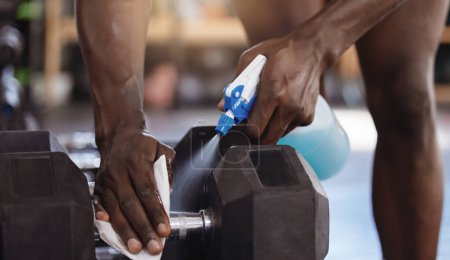 Photo for Gym, cleaning or man hands with sanitizer for dumbbell, safety or prevention of germs, virus and bacteria. Weights, spray or sports club member with dust cloth, liquid or hygiene of workout equipment. - Royalty Free Image