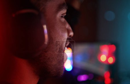 Juegos, auriculares y hombre en esports en la noche en competencia con los videojuegos en línea. Gamer, nerd y persona en habitación oscura con luces de neón y concurso cibernético de transmisión en vivo en el ordenador en casa.