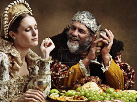 Photo for King, queen and royalty with feast and wine in banquet hall for fine dinning for tradition or culture in palace. Monarch, sovereign and together with buffet for luxury, bored and vintage with goblet - Royalty Free Image