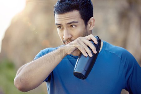 Photo for Fitness, asian man and bottle for running, rest or fatigue in outdoor workout. Sport, drinking water and male athlete person wiping mouth for training, exercise or marathon trail in sunshine. - Royalty Free Image