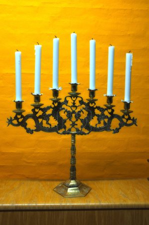 Candle, vintage and holder in church on table at interior of room or cathedral. Wax, brass and retro candlestick for decoration at temple, wood and copper metal with antique candelabra for lighting.