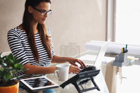 Photo for Woman, desk and computer with blueprints for interior design or creative career, happy and working on graphics on laptop. Online, search and plan project with digital technology and information. - Royalty Free Image