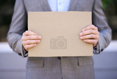 Photo for Unemployment, blank and hands with cardboard, outdoor and adult with poverty as auditor. Person, search and job hunting for work with sign on street in city of Cape Town, career and poster for mockup. - Royalty Free Image