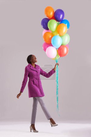 Photo for Balloon, fashion and happy black woman in studio for birthday, celebration and present. Style, excited and isolated person smile with inflatables for party, gift and surprise on gray background. - Royalty Free Image
