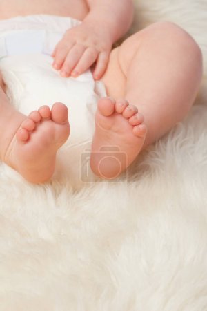 Photo for Baby feet, cute and toes in bedroom, blanket and playtime in diaper for child development in skin care. Infant, kid and wellness for newborn, adorable and rug in house for home and toddler fun. - Royalty Free Image