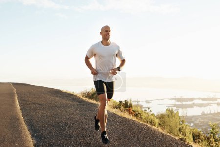 Téléchargez les photos : Fitness, course et l'homme sur la route en montagne pour la santé, le bien-être et le développement du corps forte. Entraînement, exercice et coureur sur le chemin de la nature pour l'entraînement au marathon, la performance et le défi sur la colline - en image libre de droit