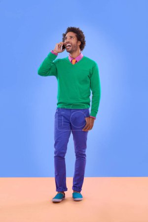 Photo for Fashion, black man and phone call in studio for color block in trendy clothes, style and outfit. Male person, stylist and fashionable for season trends with funky, edgy and formal wear in happiness. - Royalty Free Image