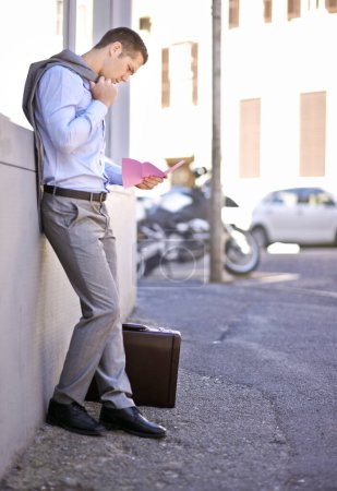 Photo for Business, job loss and man on street, fired and reading letter of unemployment on city sidewalk. Anxiety, mental health and sad businessman on road with termination notice, briefcase and pink slip. - Royalty Free Image