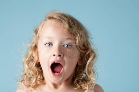 Studio, child or girl in portrait with shock, expression and isolated on blue background. Model, backdrop and kid for announcement with face reaction of wow, omg and surprised emoji with mind blown.