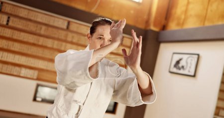 Photo for Aikido class, woman and fight for martial arts, strike or together for combat at training, gym or dojo. Japanese person, student and hands for exercise, workout or fitness with zen, conflict or club. - Royalty Free Image