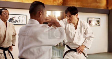 Photo for Japanese master, student or fighting in martial arts in dojo place, block or training in aikido class in self defence. Commitment, battle and fitness in skill, black belt and discipline in respect. - Royalty Free Image