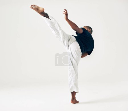 Photo for Man, studio and martial arts for kick fight, action and karate exercise on white background. Black male person, mockup space and training for combat, fitness and position of attack in taekwondo. - Royalty Free Image