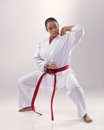 Photo for Woman, training and karate fighter in studio, fitness and martial arts on white background. Black person, athlete and red belt for taekwondo, discipline and warrior ready for self defense or battle. - Royalty Free Image