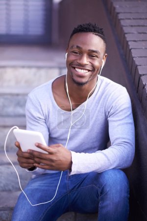 Photo for Black man, portrait and earphones or technology for music in city or sitting on steps, streaming or connection. Male person, social media and texting or downtown in Atlanta, relax or subscription. - Royalty Free Image