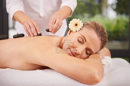 Photo for Person, spa and hands with hot stone for massage, wellness and relax in hotel. Physical therapy, holistic and woman or girl in holiday or vacation in California for health, peace and back skin detox. - Royalty Free Image