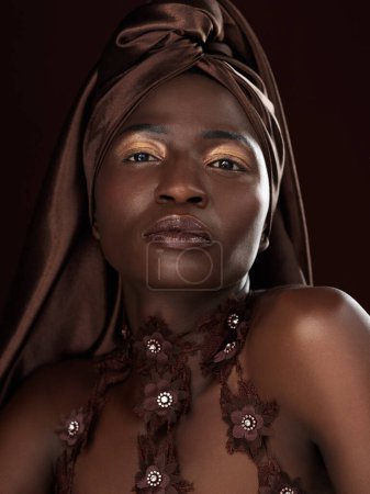 Foto de Mujer negra, envoltura y retrato en estudio para moda, belleza natural y maquillaje sobre fondo oscuro. Cosméticos, confianza y modelo femenino africano con bufanda tradicional, accesorios o glamour. - Imagen libre de derechos