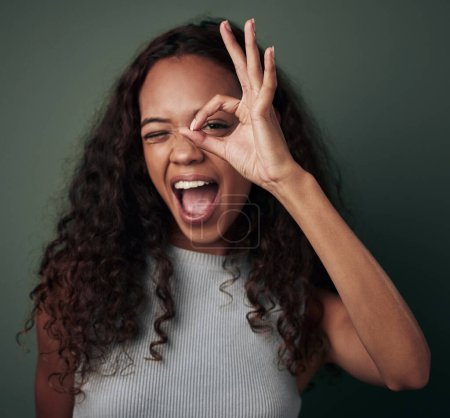 Photo for Circle, hand and portrait of black woman in studio for peek a boo or i see you, perfect sign and wow. Girl, isolated and green background with ok gesture for feedback and expression with approval - Royalty Free Image
