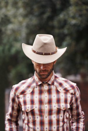 Foto de Vaquero, sombrero y hombre para la moda, granjero y ropa para el oeste y rancho en Texas para rodeo en maqueta. Joven y serio con camisa a cuadros y atractivo para la cultura, el estilo y la tendencia. - Imagen libre de derechos
