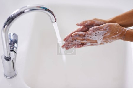 Téléchargez les photos : Femme, savon et lavage des mains dans la salle de bain pour l'hygiène, les soins de la peau ou les bactéries à la maison avec bien-être. Personne, mousse et désinfection pour la protection des germes, la routine ou les soins de santé avec de l'eau courante par évier. - en image libre de droit