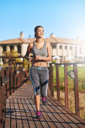 Photo for Outdoor, running and exercise for girl, fitness and workout in morning, summer and energy in bridge. Park, runner and female person in sportswear, cardio and training in nature, smile and speed. - Royalty Free Image