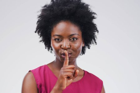 African woman, portrait and gesture with secret, studio and silence for mystery announcement. Model, gossip and hush with rumor, whisper and finger for news or noise with privacy on white background.